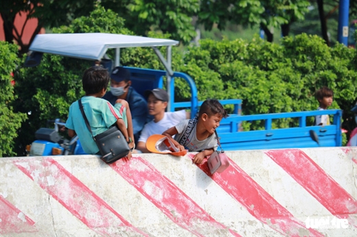 Những đứa trẻ hồn nhiên trèo qua dải phân cách ngay trên xa lộ Hà Nội, Q.2, TP.HCM - Ảnh: NGỌC PHƯỢNG