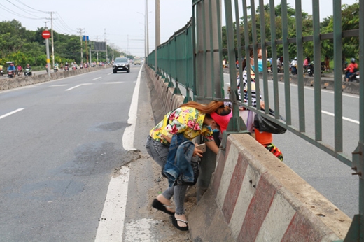 Trước một công ty tại Q.Bình Tân, TP.HCM, người đi bộ cũng chui cắt ngang dải phân cách trên QL1A để qua đường - Ảnh: NGỌC PHƯỢNG