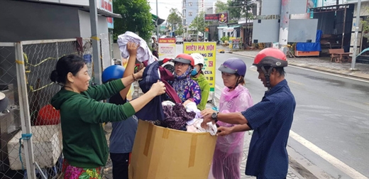 Người dân đến thay nhớt xe tranh thủ lựa quần áo về mặc sau mấy ngày chịu ướt - Ảnh: DUY KHÁNH