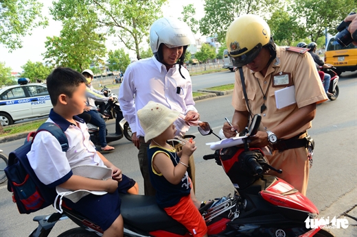 Cảnh sát giao thông xử phạt một trường hợp chở trẻ không đội mũ bảo hiểm trên đường Võ Văn Kiệt, Q.5, TP.HCM - Ảnh: QUANG ĐỊNH