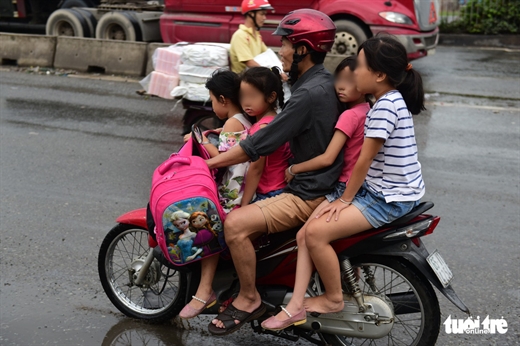 Vô tư chở 4 trẻ em không mũ bảo hiểm lại còn chạy ngược chiều trên quốc lộ - Ảnh: QUANG ĐỊNH