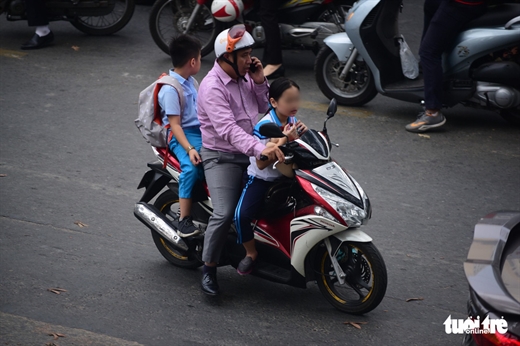 Một phụ huynh vừa nghe điện thoại vừa chở trẻ không đội nón bảo hiểm trên đường Nguyễn Thị Minh Khai, Q.3, TP.HCM - Ảnh: QUANG ĐỊNH