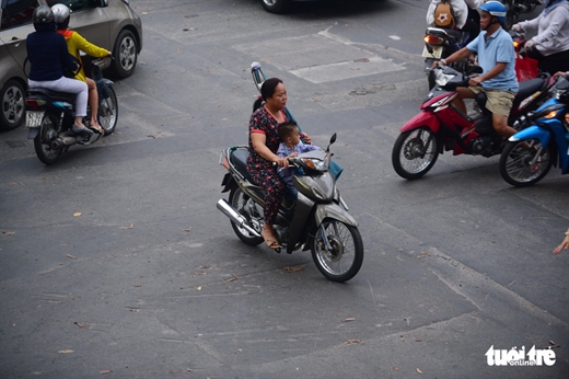 Làm xiếc khi một tay cầm lái, một tay cầm đồ trên đường Nguyễn Thị Minh Khai, Q.3, TP.HCM. Thật đáng lo cho tính mạng đứa bé - Ảnh: QUANG ĐỊNH