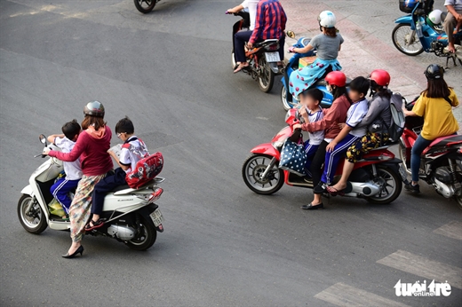 Chở trẻ không đội mũ bảo hiểm mà còn dừng xe không đúng vạch quy định khi chờ đèn đỏ trên đường Nguyễn Bỉnh Khiêm, Q.1, TP.HCM - Ảnh: QUANG ĐỊNH