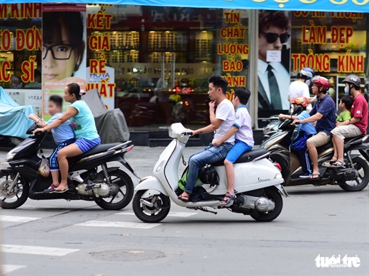 Phụ huynh có mũ bảo hiểm nhưng không thèm đội. Ảnh chụp trên đường Trần Quang Khải, Q.1, TP.HCM - Ảnh: QUANG ĐỊNH