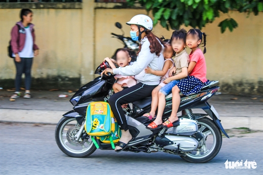 Người phụ nữ chở 4 đứa trẻ nhưng không em nào được mang mũ bảo hiểm - Ảnh: THANH YẾN