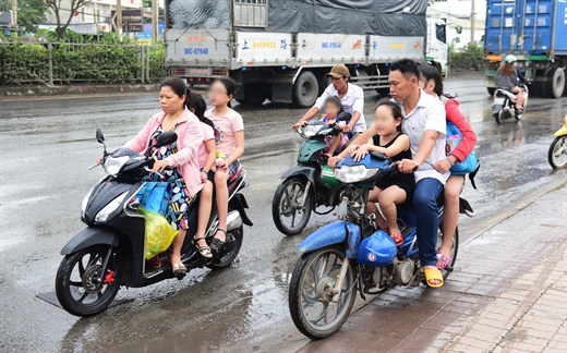 Đón con tan học, phụ huynh không đội mũ bảo hiểm và chở trẻ cũng không mũ bảo hiểm chạy ngược chiều trên quốc lộ 1A đoạn qua quận 12, TP.HCM - Ảnh: QUANG ĐỊNH