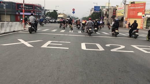 Nhóm người đi xe đạp tốc độ cao lạng lách, vượt qua một giao lộ trên đường Phạm Văn Đồng - Ảnh: LÊ PHAN