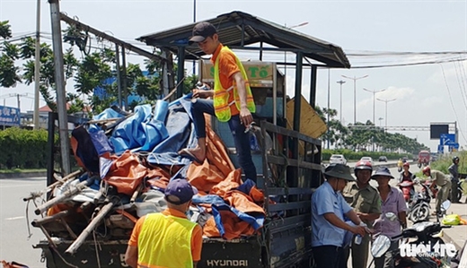 Lực lượng chức năng tháo dỡ dãy quán tạm bợ tại khu vực trạm chờ xe buýt gần cầu bộ hành KDL Suối Tiên trưa 17-10 - Ảnh: MINH HÒA