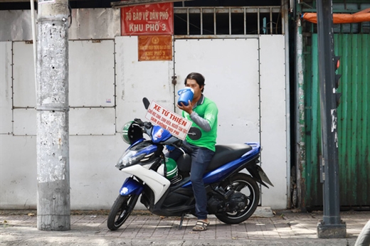 Sau những chuyến xe, anh Quí nghỉ tạm bên vệ đường ở quận Phú Nhuận chờ khách - Ảnh: NGỌC PHƯỢNG